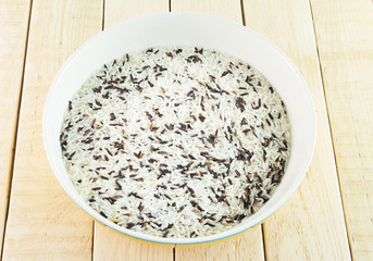 Rice brown in a ceramic bowl with wooden background.