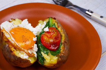 Baked potato with fried egg, feta, spinach and tomato cherry