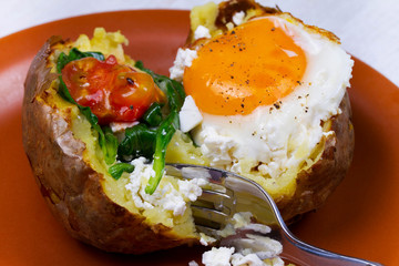 Baked potato with fried egg, feta, spinach and tomato cherry