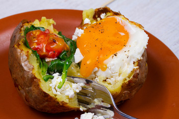Baked potato with fried egg, feta, spinach and tomato cherry