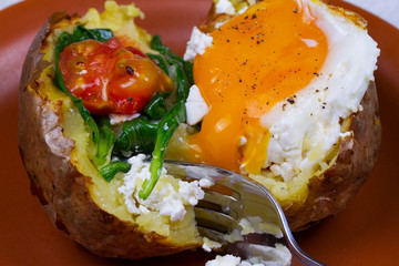 Baked potato with fried egg, feta, spinach and tomato cherry
