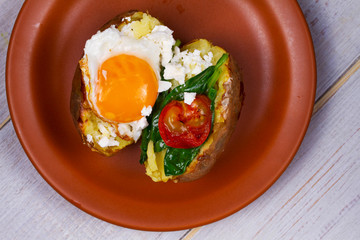 Baked potato with fried egg, feta, spinach and tomato cherry