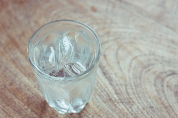 Drinking water with ice in glass on wooden table