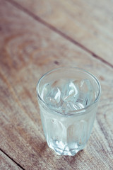 Drinking water with ice in glass on wooden table