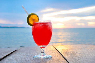 Cocktail drink on wood table in twilight sea & sky background
