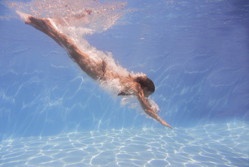 female swimmer after jumping with air bubbles trail