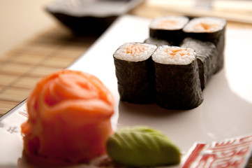 Sushi rolls with salmon on a white plate decorated ginger rose