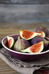Ripe figs in a bowl on wooden background