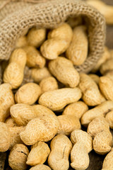 peanuts in a miniature burlap bag on wooden surface