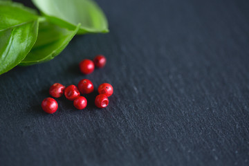 basil and pink peppercorns on black background