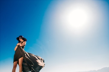 beautiful girl in black long dress on a background of blue sky