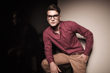 Obraz premium Handsome young casual man sitting on a stool