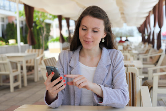 Girl using smart phone in a restaurant terrace