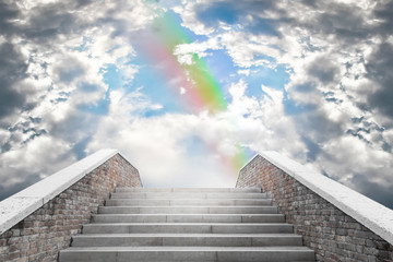 Marble staircase leading to the cloudy sky and rainbow