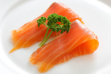 Salmon slices with parsley on a white plate.