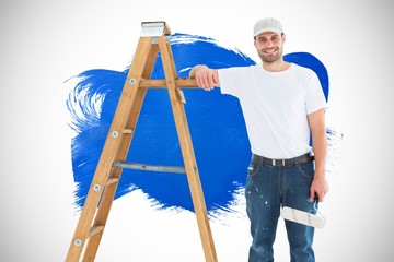 Happy man with paint roller standing by ladder