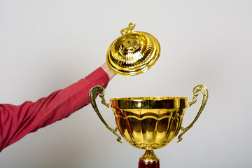 Hand opens lid of gold cup
