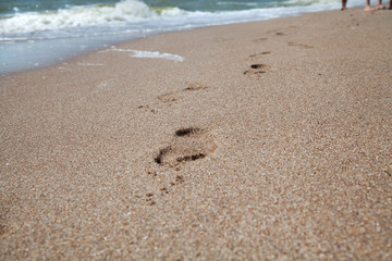 Traces of bare feet on wet sea sand