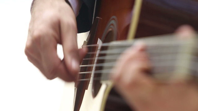 european man plays guitar with focus moving along neck	