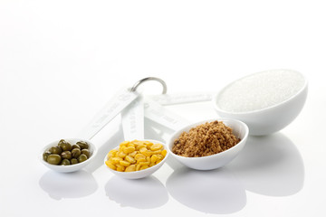 Beans in measuring spoons on white background