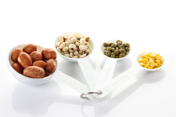 Beans in measuring spoons on white background