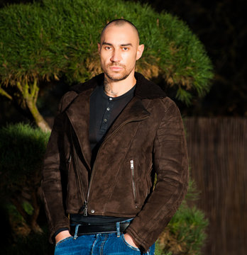  young man in brown leather jacket pose in parck