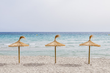 Straw umbrellas on sand beach.