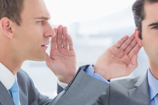 Businessman telling secret to his colleague