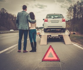 Couple near tow-truck picking up broken car
