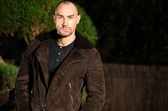  young man in brown leather jacket pose in parck