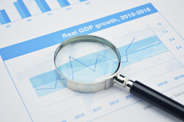 Fototapeta premium Magnifying glass on financial graph, accounting background
