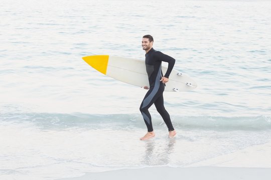 Man in wetsuit with a surfboard on a sunny day