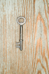 Old key from the lock on a wooden texture