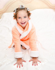 Happy funny little girl with manicure and hair curlers