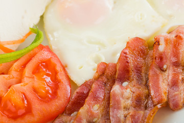 Fried eggs coloseup with bacon and vegetables