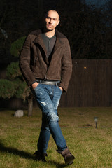 Attractive young man in a brown leather jacket pose in parck