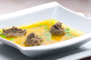 homemade liver dumplings in chicken soup with carrots and peas