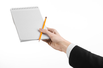 hand in a black suit holding a notebook with a pencil