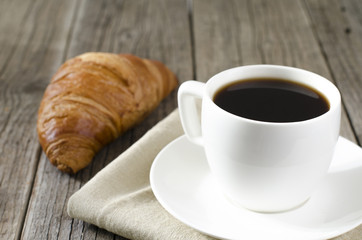 cup of coffee on a wooden table and croissant