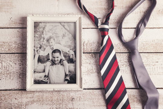 Picture frame with family photo and ties on wooden background.