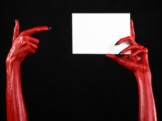 Red devil hand with black nails holding a blank white card