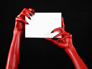 Red devil hand with black nails holding a blank white card