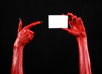 Red devil hand with black nails holding a blank white card