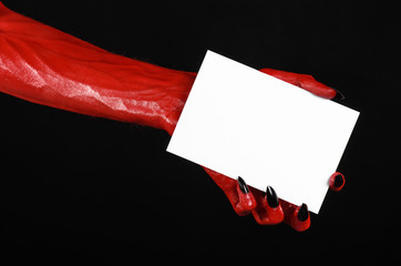 Red devil hand with black nails holding a blank white card