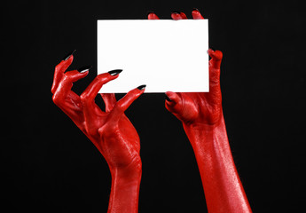 Red devil hand with black nails holding a blank white card
