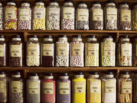 Traditional sweets displayed in tall glass jars on the shelves of a sweet shop. 