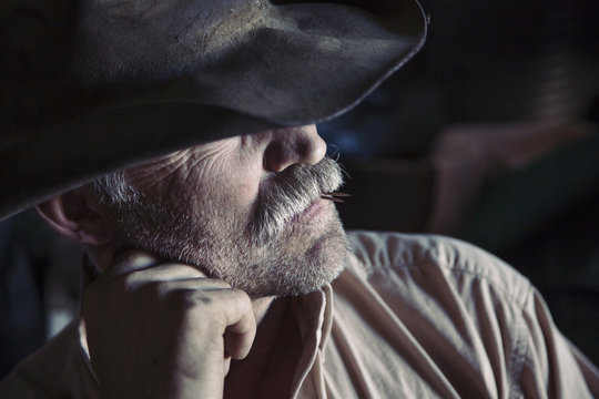 Man wearing brimmed hat with chin on hand