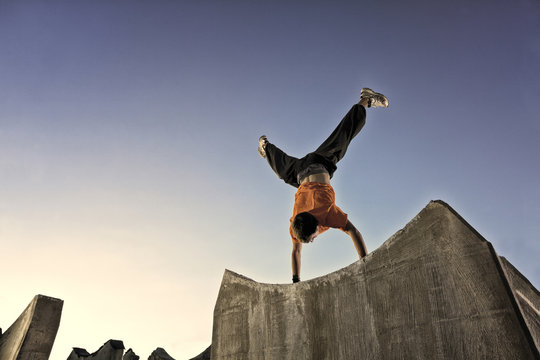 Man doing parkour handstand in urban setting