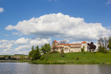 Naklejka na ściany i meble old castle and green reflection in blue water with cloudy sky background