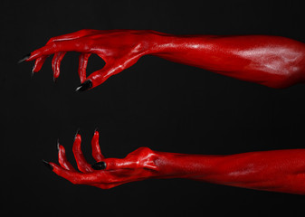 Red Devil's hands, red hands of Satan, black background isolated